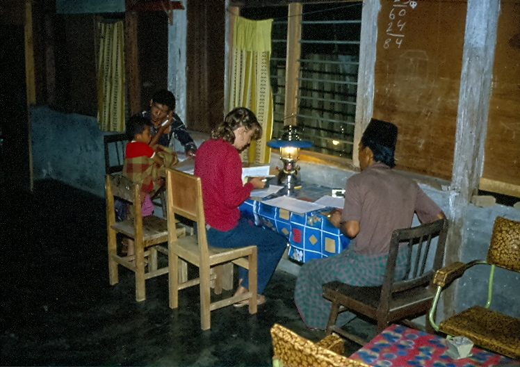 B. Röttger-Rössler writing up the evening's notes in the field near Petromax Lampe, with research participants at her side who commented on everything that was written, Martin Rössler, 1984, All rights reserved